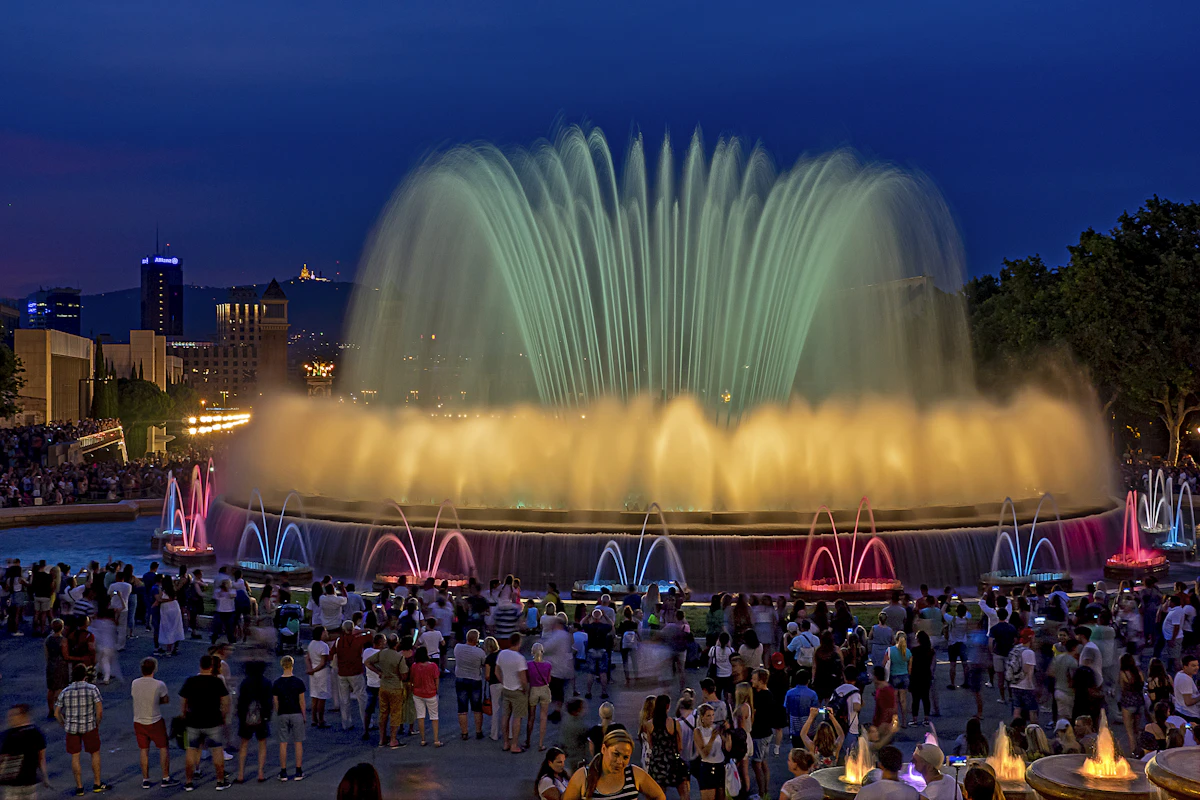 La Fontaine Magique de Montjuïc à Barcelone illuminée de nuit, avec le Palau Nacional et les lumières de la ville en arrière-plan