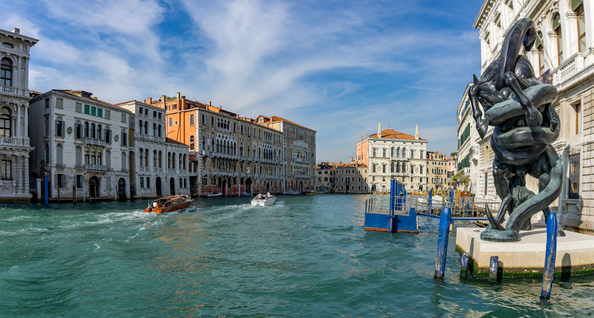 Uma grande instalação escultórica contemporânea em bronze na ponta da Punta della Dogana, no Grande Canal de Veneza, com o antigo edifício da alfândega da Coleção Pinault e palácios ao longo da água ao fundo