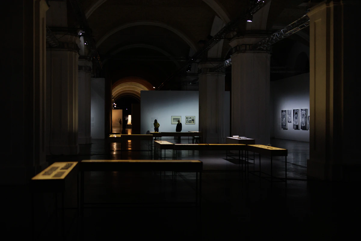 قاعة عرض تضم طاولات ولوحات على الجدران (صورة تمثيلية، وليست الصورة الفعلية لمبنى Pinakothek der Moderne)