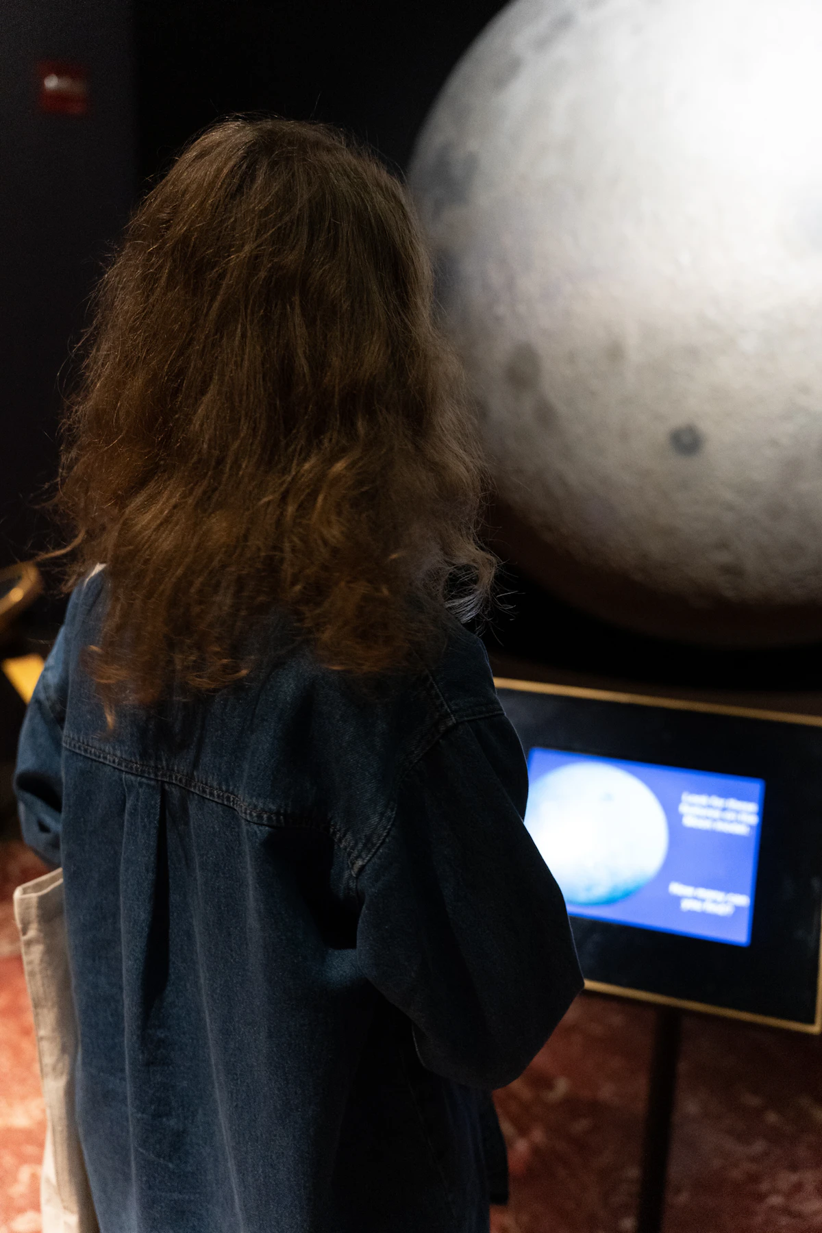 Ein Kind betrachtet ein beleuchtetes Planetenmodell in einer Weltraum-Ausstellung (repräsentatives Bild, nicht die tatsächliche Kuppel oder das Innere des Planetariums Hamburg)