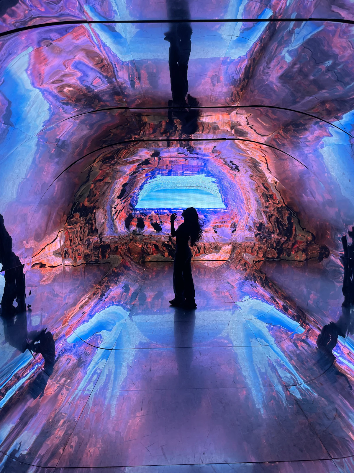 Eine Person im Silhouette vor einer bunten abstrakten digitalen Kunstinstallation (repräsentatives Bild, nicht das tatsächliche Frameless-Erlebnis)