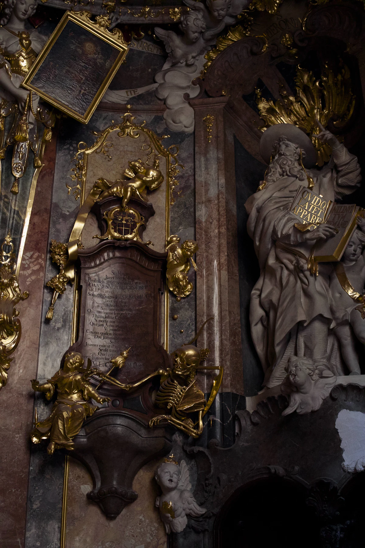 Uno scheletro dorato memento mori sotto un ornato monumento in oro e marmo all'interno dell'Asamkirche di Monaco