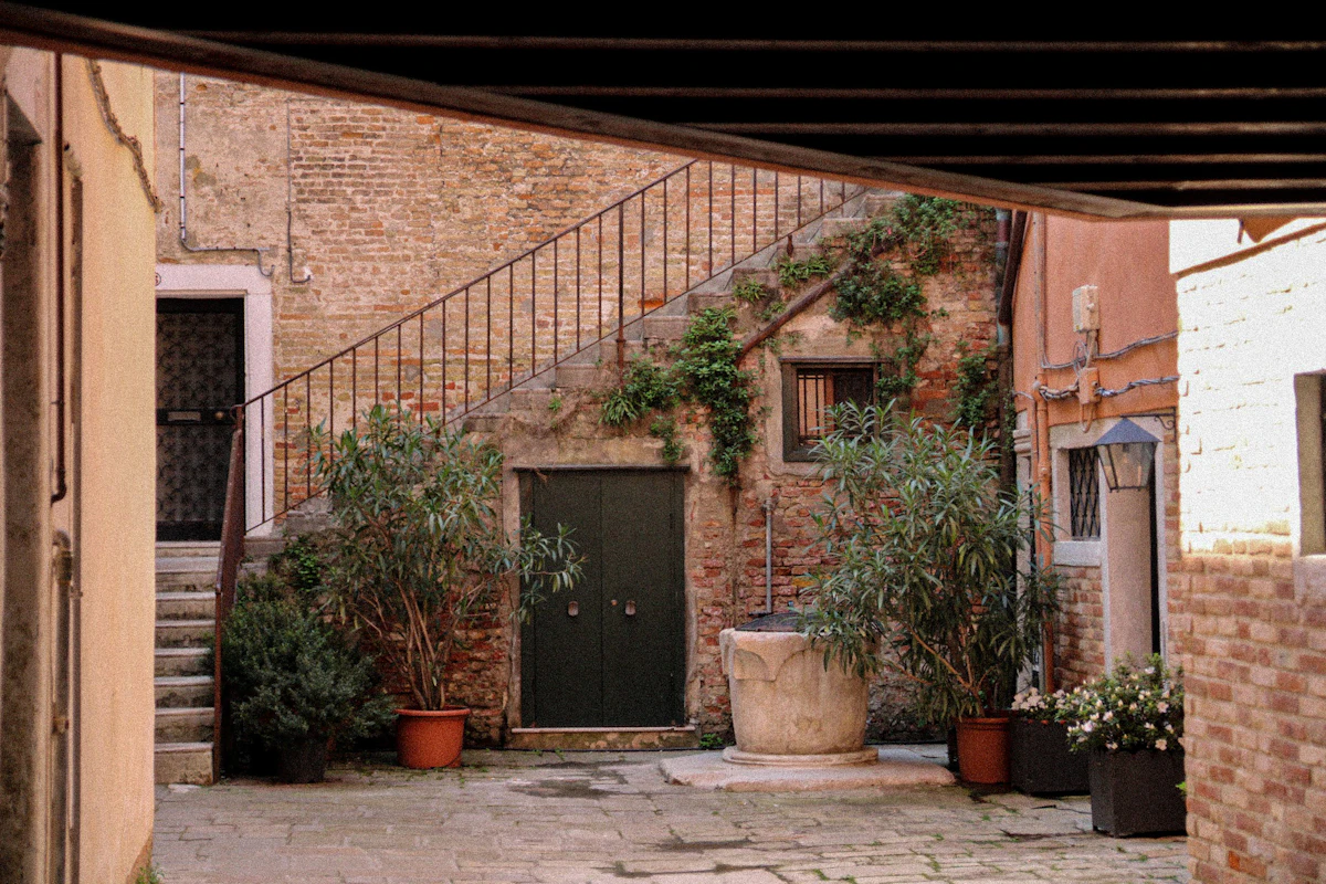 Ein kleiner gotischer venezianischer Innenhof mit einem Brunnenschacht, typisch für ein historisches venezianisches Adelshaus (repräsentatives Bild, nicht zwingend die tatsächliche Casa di Carlo Goldoni)