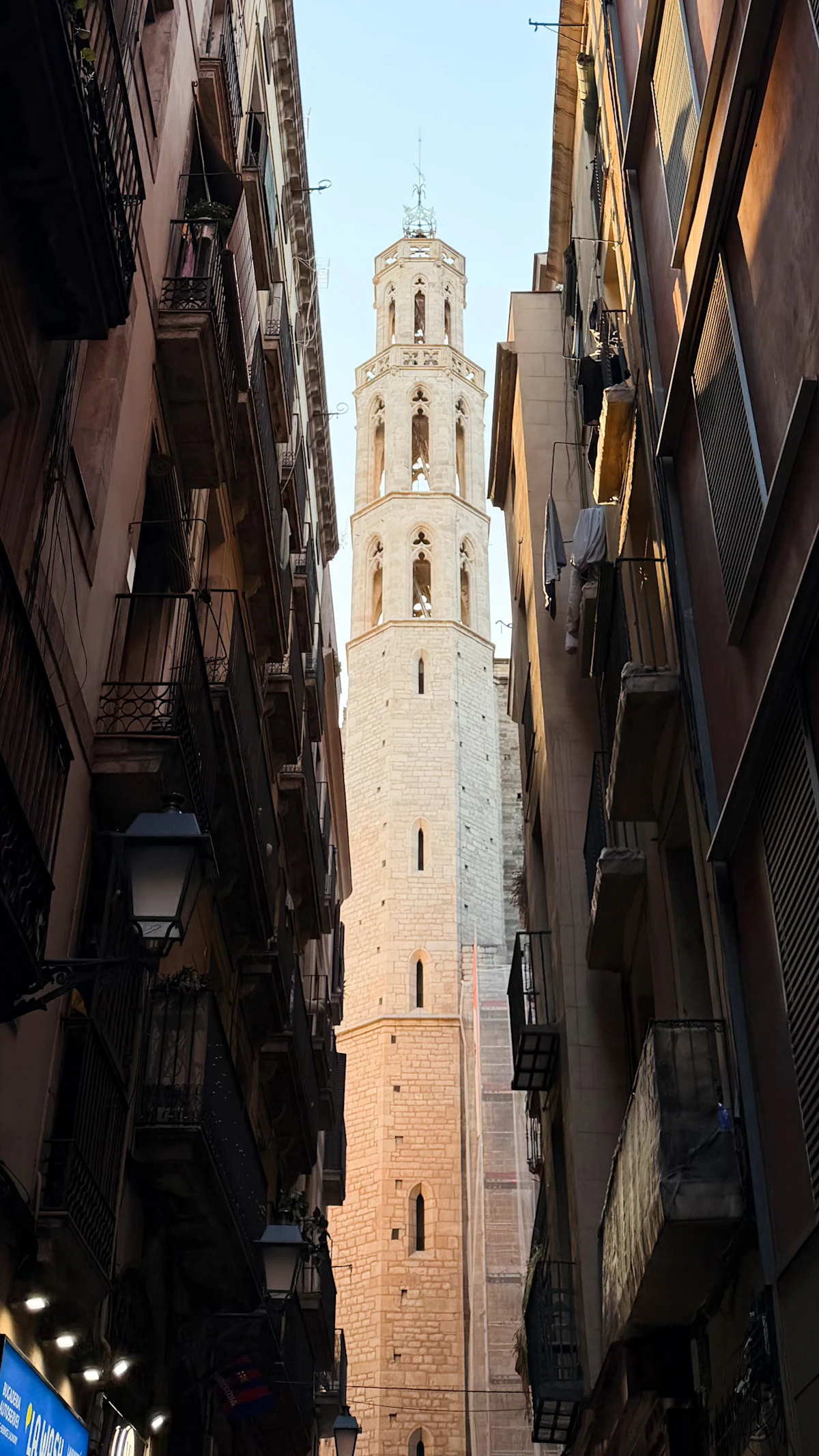 O campanário da Basílica de Santa Maria del Mar a erguer-se entre os edifícios estreitos do bairro do Born, em Barcelona